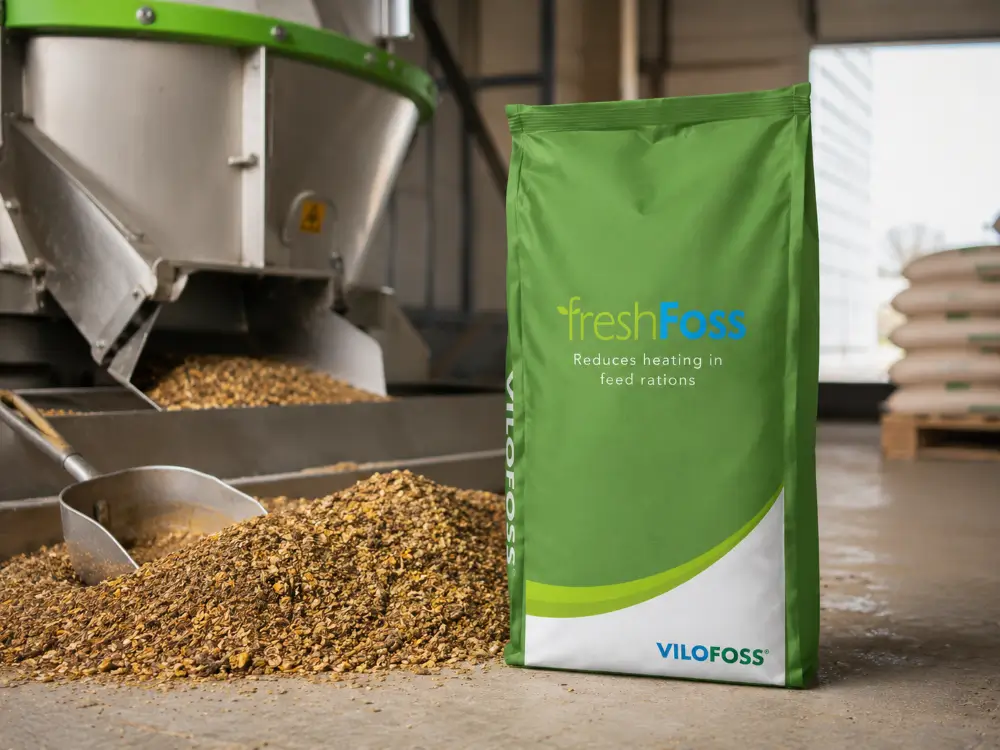 A freshFoss bag on a feed-mill floor beside a heap of milled feed, a scoop and a mixing auger.